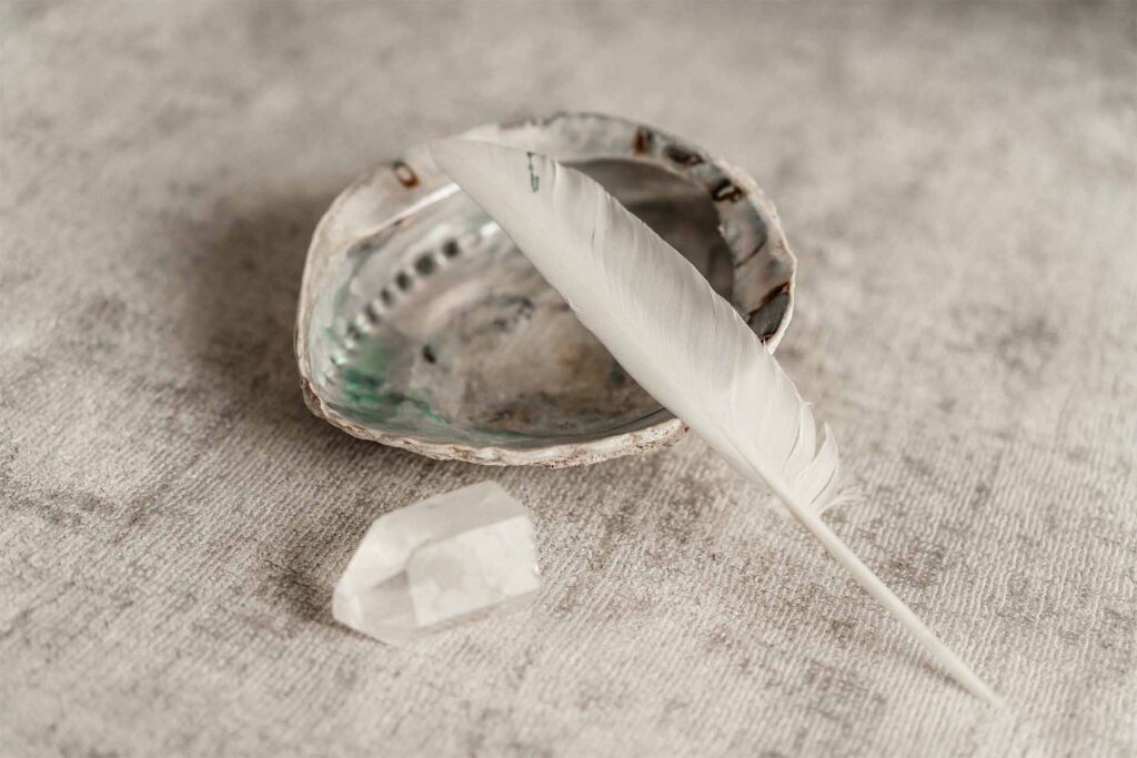 Dankbarkeit finden - Muschel mit Feder und einem liegendem Bergkristall